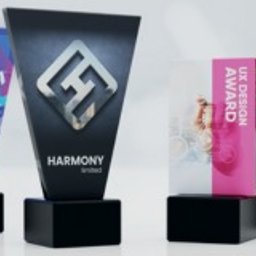PucharyiStatuetki - Cztery szklane statuetki na czarnych, kwadratowych podstawkach, każda z unikalnym nadrukiem i motywem graficznym: muzyczny festiwal, logo firmy, nagroda za projekt UX, szkolny turniej. Statuetki...