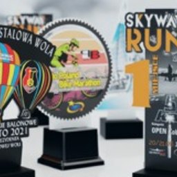 PucharyiStatuetki - Kolekcja spersonalizowanych statuetek i nagród akrylowych z różnymi motywami: balony, rower, bieg, samolot, w kolorystyce czerni, bieli, czerwieni i żółci, ustawionych na białym podłożu.