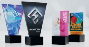 Cztery szklane statuetki na czarnych, kwadratowych podstawkach, każda z unikalnym nadrukiem i motywem graficznym: muzyczny festiwal, logo firmy, nagroda za projekt UX, szkolny turniej. Statuetki...