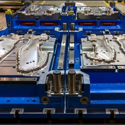 M.C.S. POLSKA SPÓŁKA Z OGRANICZONĄ ODPOWIEDZIALNOŚCIĄ - Forma wtryskowa do tworzyw sztucznych, dwuczęściowa, z widocznymi detalami obróbki, osadzona w niebieskiej ramie, widok z góry pod kątem.