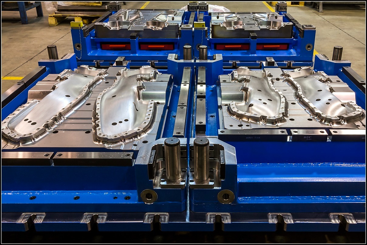 Forma wtryskowa do tworzyw sztucznych, dwuczęściowa, z widocznymi detalami obróbki, osadzona w niebieskiej ramie, widok z góry pod kątem.