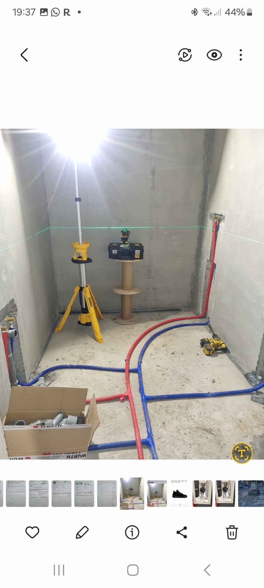 Wnętrze w trakcie instalacji hydraulicznej: widoczne rury PEX w kolorach niebieskim i czerwonym, poziomica laserowa DeWalt na statywie, karton z kształtkami Würth, oraz narzędzia na podłodze...