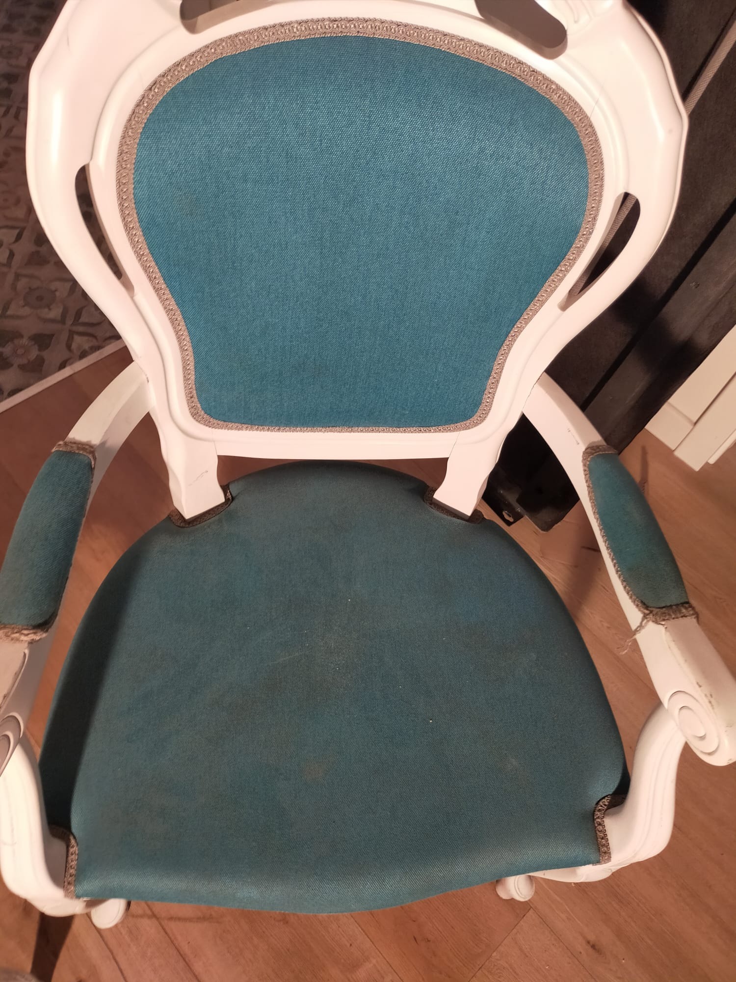 Krzesło z białymi zdobieniami i turkusową tapicerką widziane z góry, widoczne plamy na siedzisku.
