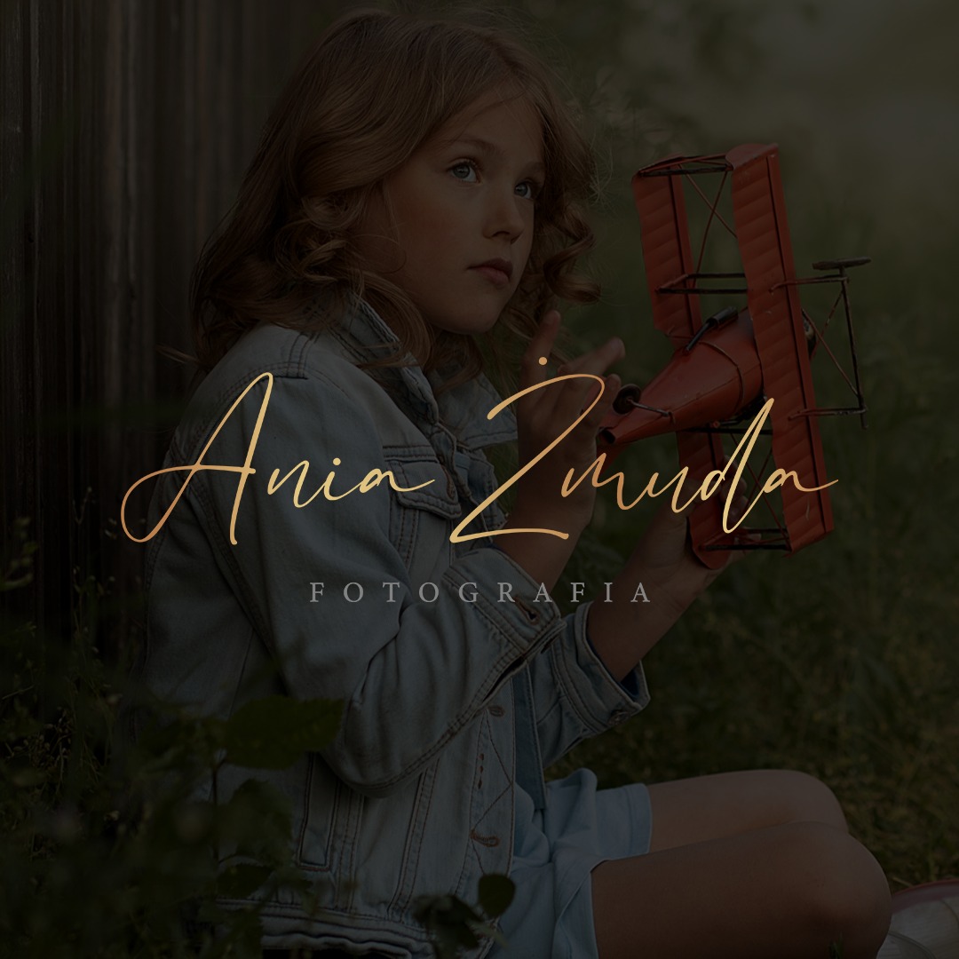 Portret dziewczynki z rudym modelem samolotu, w tle drewniane ogrodzenie i złoty napis 'Ania Zmuda FOTOGRAFIA'.