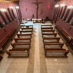 DAMIAN KAPUSZ SPEŁNIAMY WASZE MARZENIA D&M - Wnętrze kościoła z drewnianym stropem i ceglanymi ścianami, z rzędami drewnianych ławek na marmurowej posadzce.