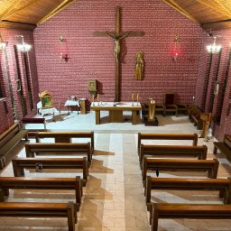 DAMIAN KAPUSZ SPEŁNIAMY WASZE MARZENIA D&M - Wnętrze kaplicy w Łące: widok z góry na drewniane ławki, marmurową posadzkę i ceglane ściany z krucyfiksem.