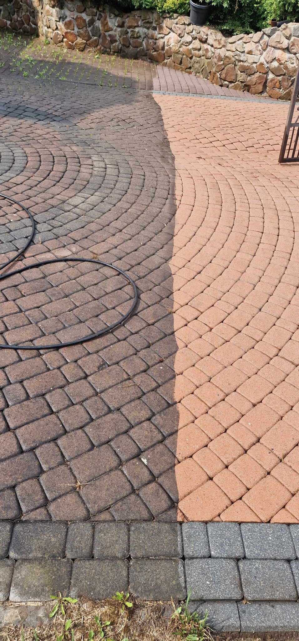 Efekt mycia kostki brukowej w Kaszowie: Połowa powierzchni wyczyszczona, ukazując różnicę w kolorze i czystości; widoczny wąż ciśnieniowy.