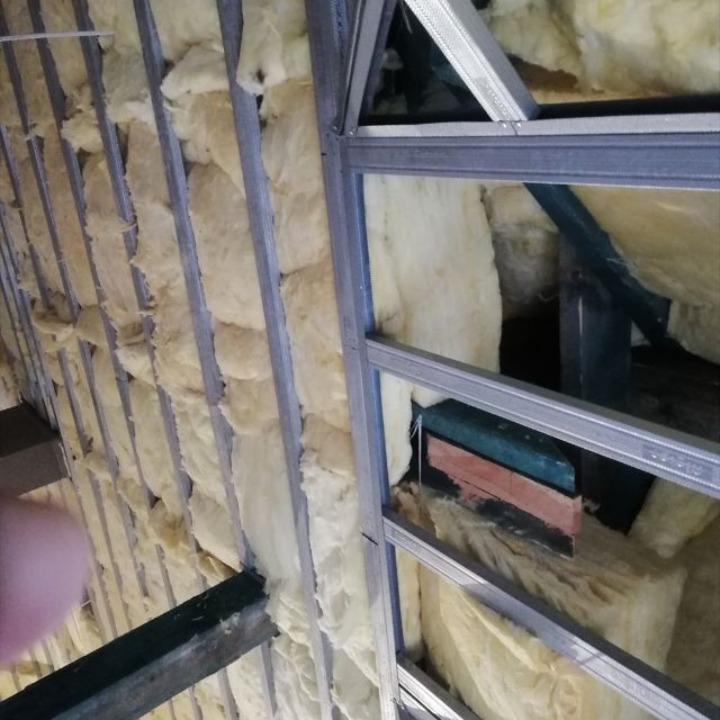 Ocieplenie wełną mineralną poddasza z widoczną metalową konstrukcją nośną. Widok z dołu na izolację termiczną.