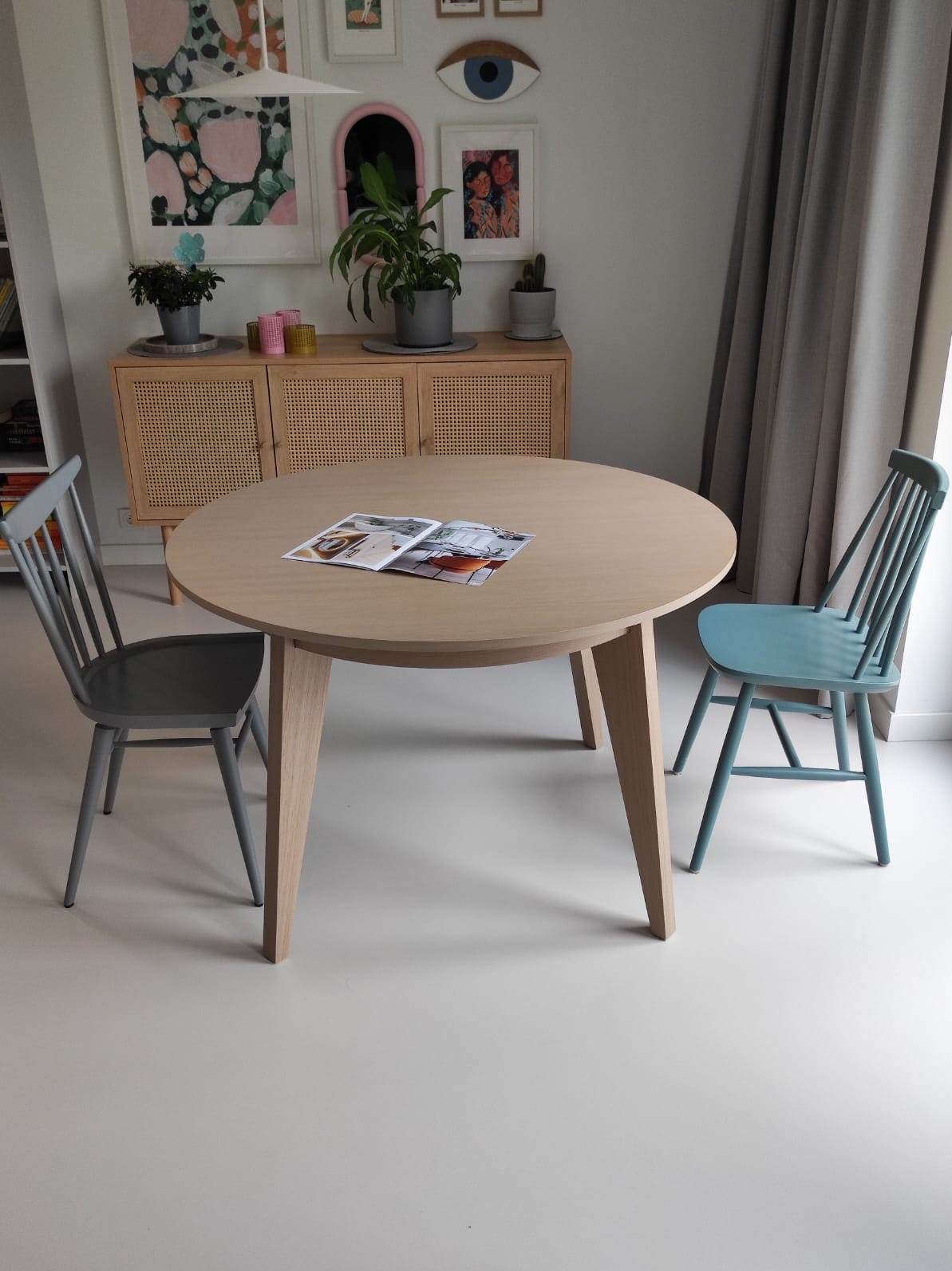 Jasna, okrągła podłoga w Lublinie, z bliska, z dwoma krzesłami w różnych odcieniach szarości i błękitu oraz okrągłym stołem z otwartą książką na nim.