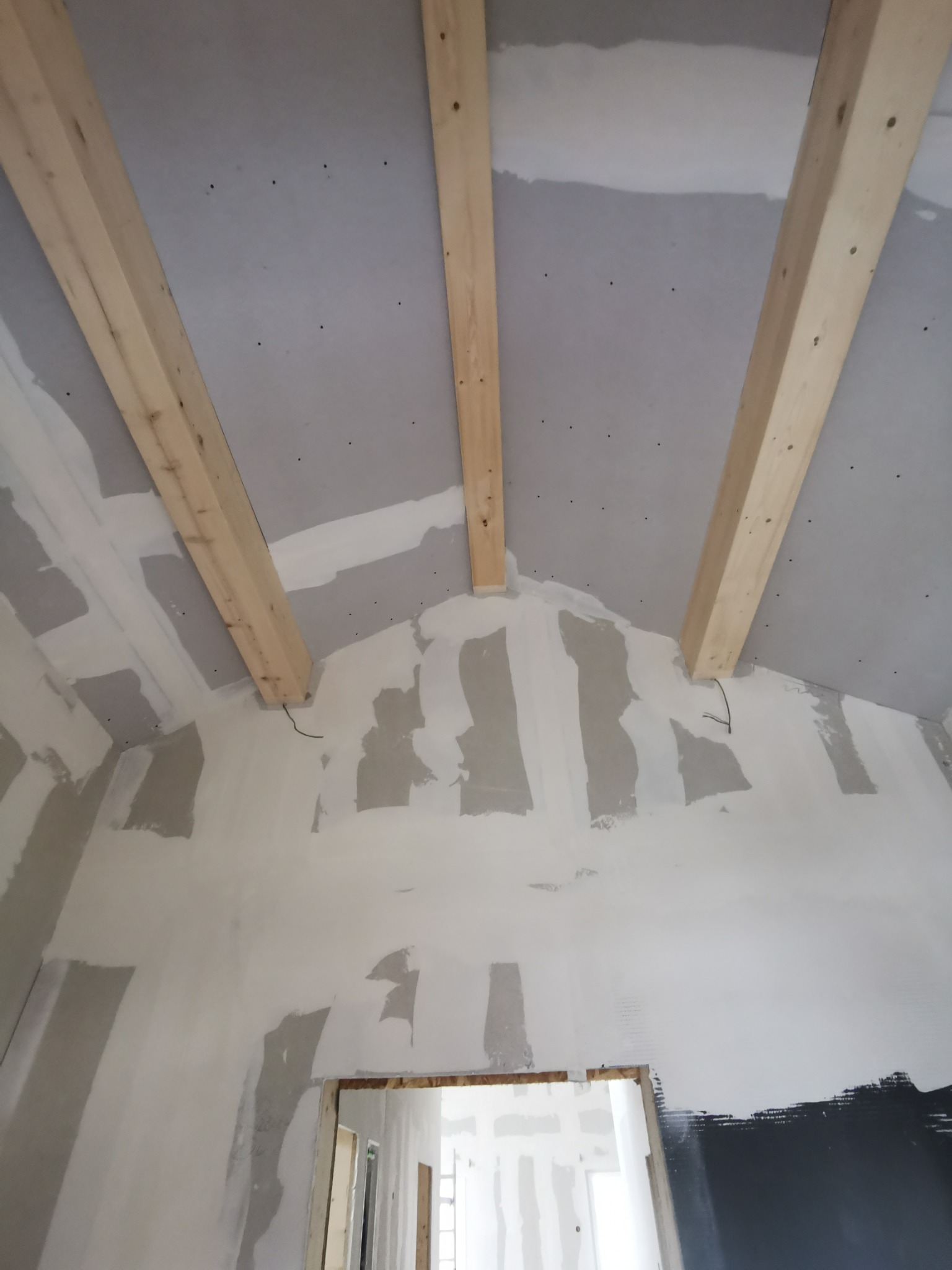 Poddasze z płytami gipsowymi i drewnianymi belkami w Kościanie. Widoczne szpachlowane łączenia płyt. Prace wykończeniowe w trakcie realizacji.
