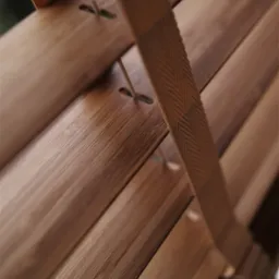 Fragment drewnianych żaluzji z bliska, widoczne poziome lamele połączone taśmą z wzorem w jodełkę i sznurkami.