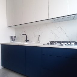 HB STUDIO Hanna Blicharska - Nowoczesna kuchnia z granatowymi szafkami dolnymi i białymi górnymi, marmurowym backsplashiem i czarną armaturą. Minimalistyczny design, neutralne kolory podłogi.