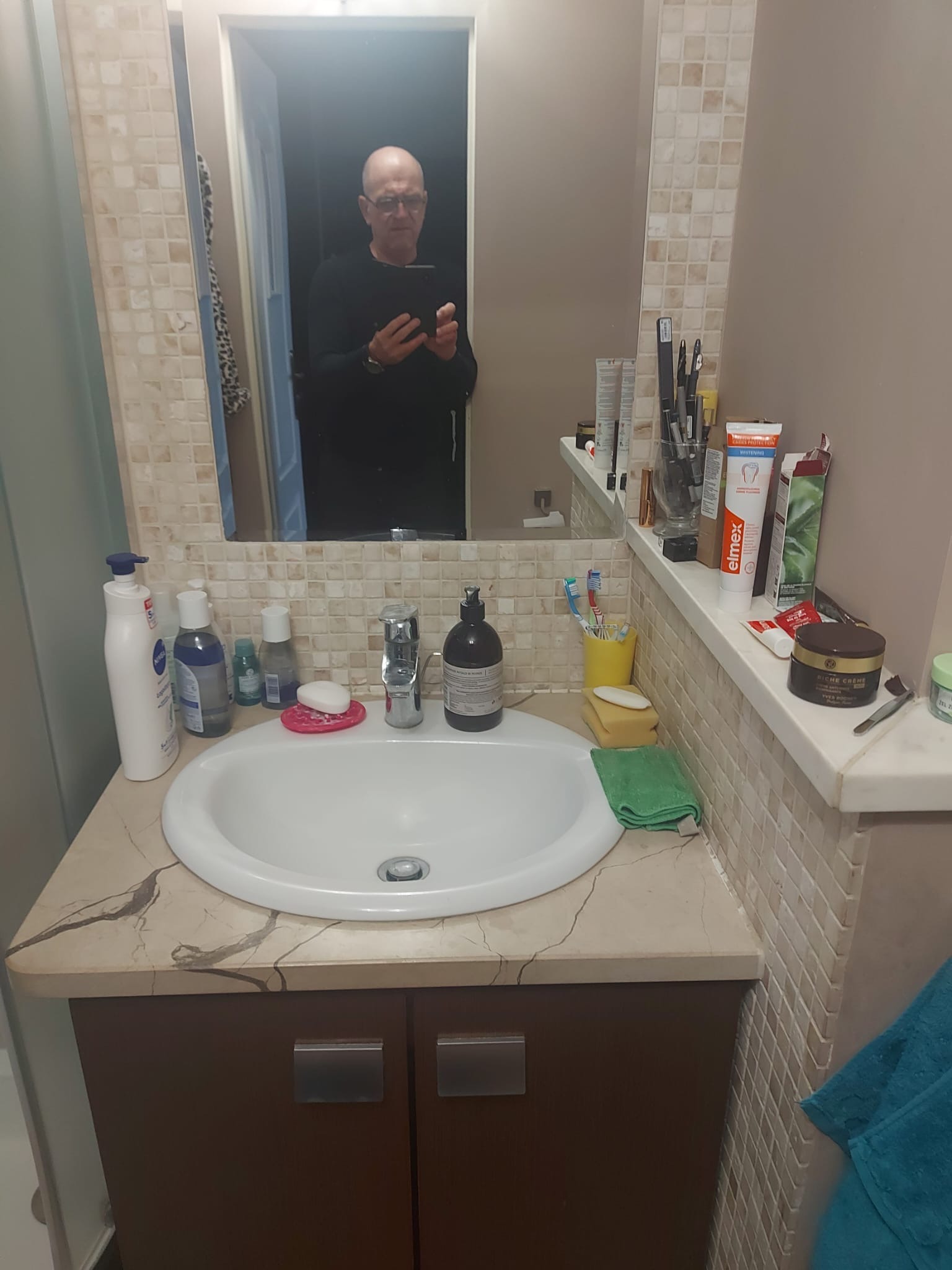 Umywalka z szafką w łazience w Bełchatowie, widoczna w lustrze osoba robiąca zdjęcie.