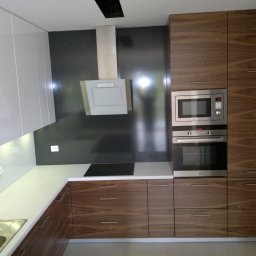 WEGA RAFAŁ ZYCH - Nowoczesna kuchnia z białymi, lakierowanymi szafkami górnymi i drewnianymi szafkami dolnymi z wyraźnym usłojeniem, wyposażona w sprzęt AGD w zabudowie i czarną płytę indukcyjną.