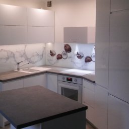 WEGA RAFAŁ ZYCH - Nowoczesna kuchnia z białymi szafkami, szarym blatem i szklanym panelem nad blatem z motywem marmuru i kokosów.