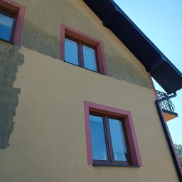 RClean - Fragment elewacji budynku z widocznym obszarem po czyszczeniu, kontrastującym z zabrudzoną powierzchnią, okna w bordowych ramach.