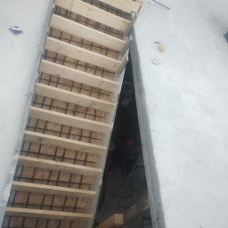 Paweł Adamczak AP-BUD - Formowanie schodów żelbetowych z drewnianym szalunkiem i zbrojeniem stalowym, widok z góry na placu budowy.