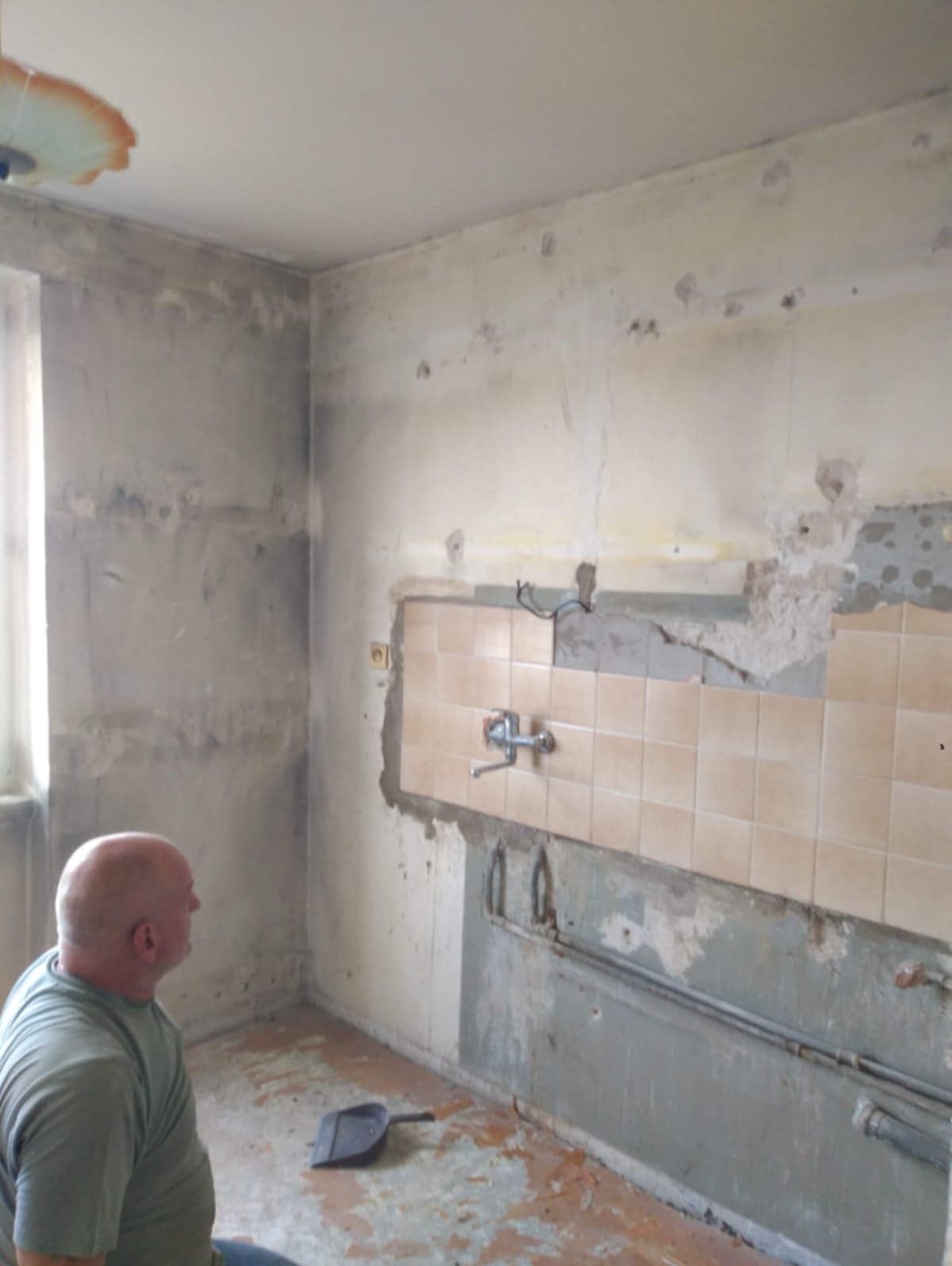 Demontaż płytek w kuchni w Dongen, widoczny fragment instalacji wodnej i resztki kleju na ścianie, przygotowanie do dalszych prac remontowych.