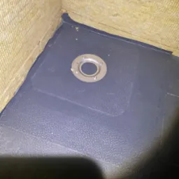 Szczelna hydroizolacja z wpustem podłogowym w rogu pomieszczenia, ściany wyłożone wełną mineralną. Detal wykończenia w trakcie prac.