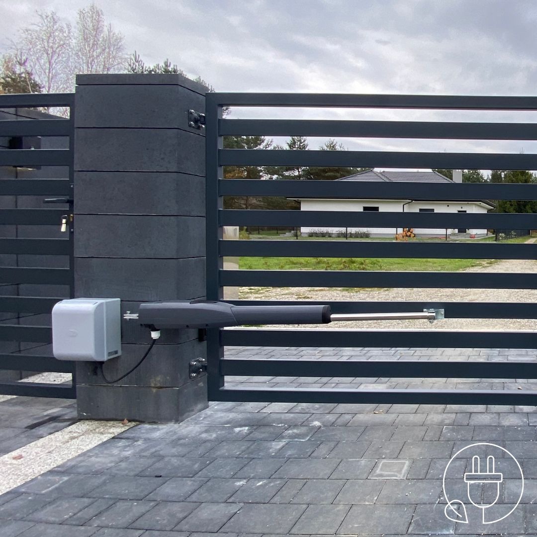 Szara, pozioma brama z automatycznym napędem zamontowanym na murowanym słupku, widok z zewnątrz na tle domu jednorodzinnego.