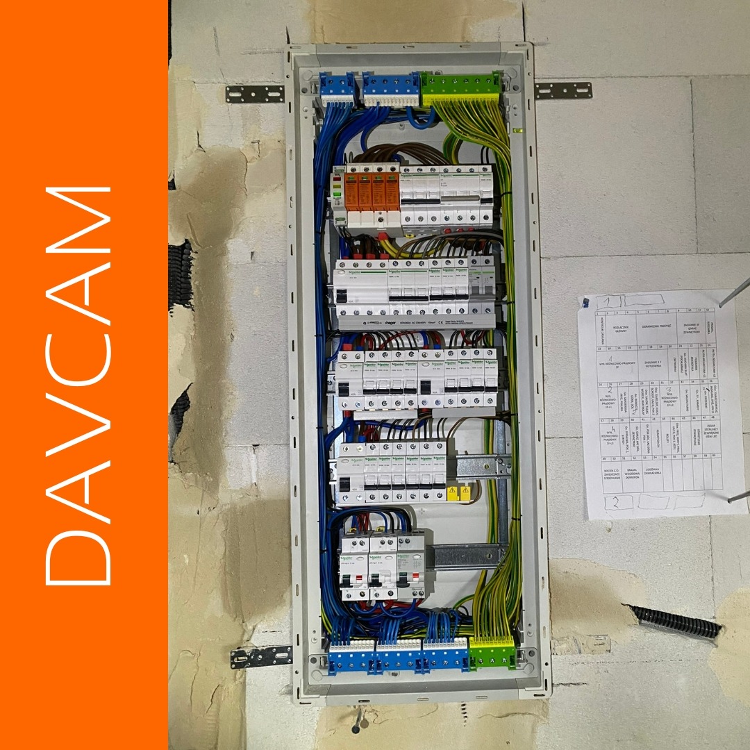 Rozdzielnica elektryczna natynkowa z zainstalowanymi bezpiecznikami, okablowaniem i schematem, zamontowana na surowej ścianie z betonu komórkowego.