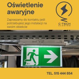 C-tech elektro Artur Rudzki - Zamontowany znak ewakuacyjny z podświetleniem LED, umieszczony pod sufitem, widoczne elementy instalacji elektrycznej i metalowa konstrukcja mocująca.