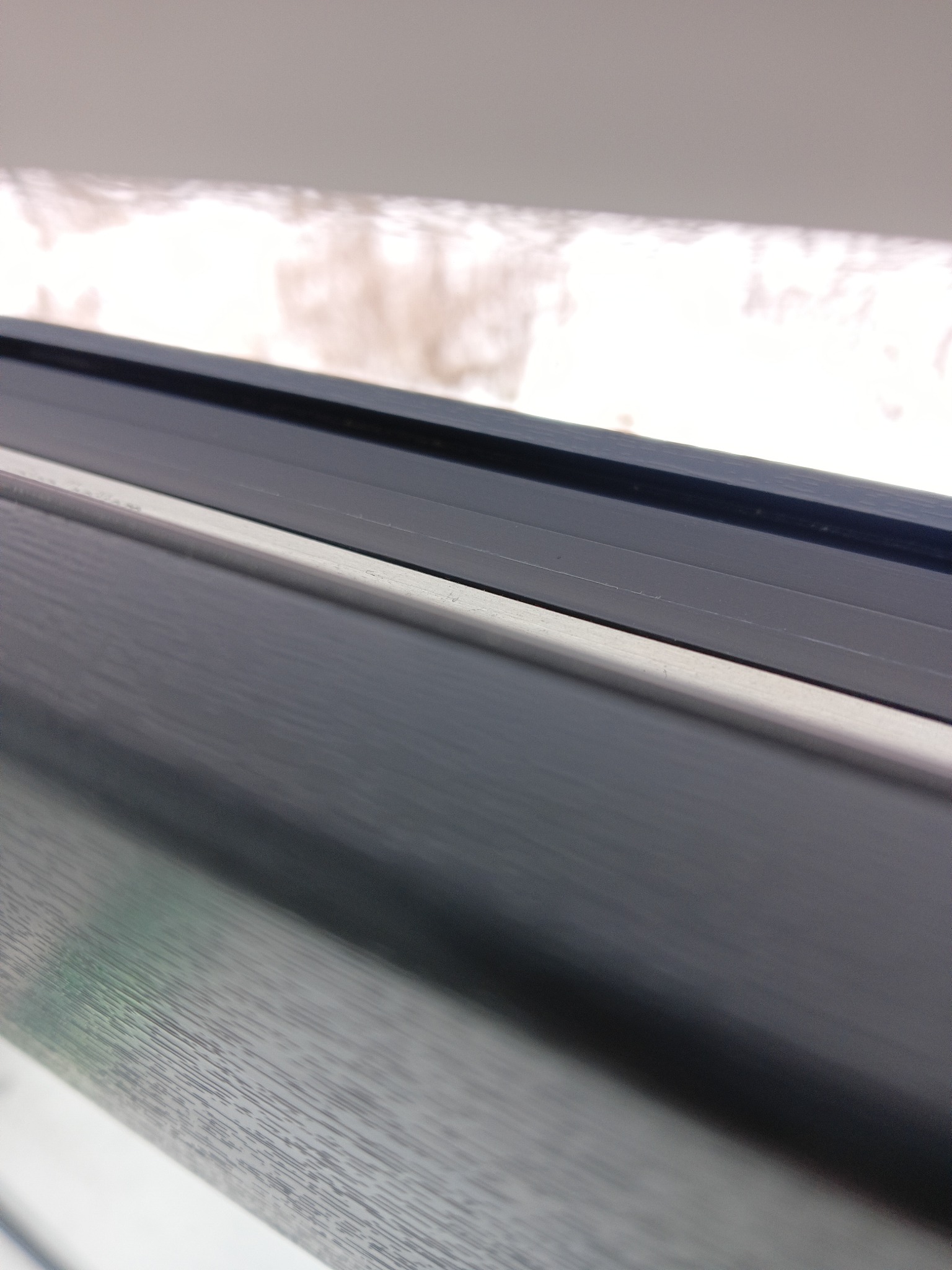 Szczegółowe ujęcie ramy okiennej z widocznym osadzonym brudem i kurzem, wymagające dokładnego czyszczenia. Widok z bliska na zabrudzenia.