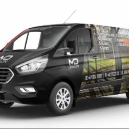 Czarny van Ford Transit z brandingiem firmy zajmującej się produkcją ogrodzeń, prezentujący wizualizację gotowych realizacji na karoserii.