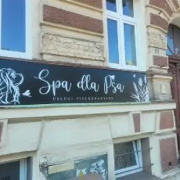 Czarny szyld z białym napisem 'Spa dla Psa Usługi Pielęgnacyjne' i rysunkami psa oraz roślin, umieszczony na fasadzie budynku z oknami i drzwiami.