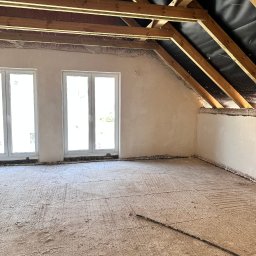 NTN CONSTRUCTION - Poddasze z drewnianą konstrukcją dachu i oknami, ściany przygotowane do tynkowania, podłoga z wylewką. Widoczne ślady po instalacjach.