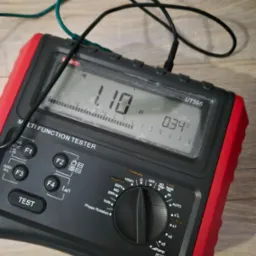 Czarno-czerwony multimetr UT595 z podłączonymi przewodami pomiarowymi, wyświetlający wartości 1.10 Ω i 0.34 V na ekranie LCD, ustawiony na pomiar ciągłości i napięcia.