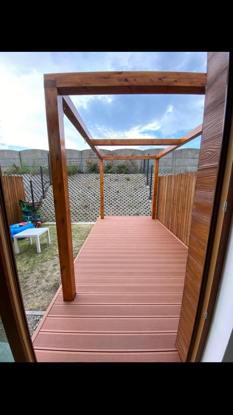 Gotowy taras kompozytowy z drewnianą konstrukcją altany w Tczewie, widok z wnętrza domu na ogród.