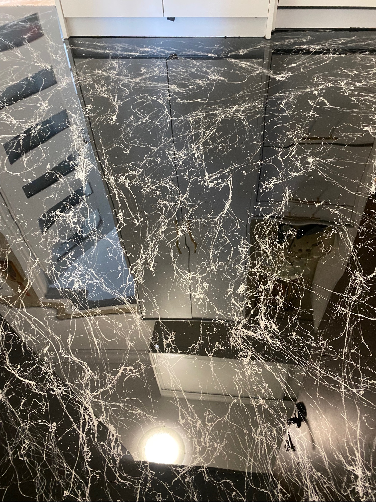 Czarna posadzka żywiczna z białymi wzorami, imitująca marmur, w mieszkaniu w Warszawie. Nowoczesny design podłogi z połyskiem i refleksami światła.