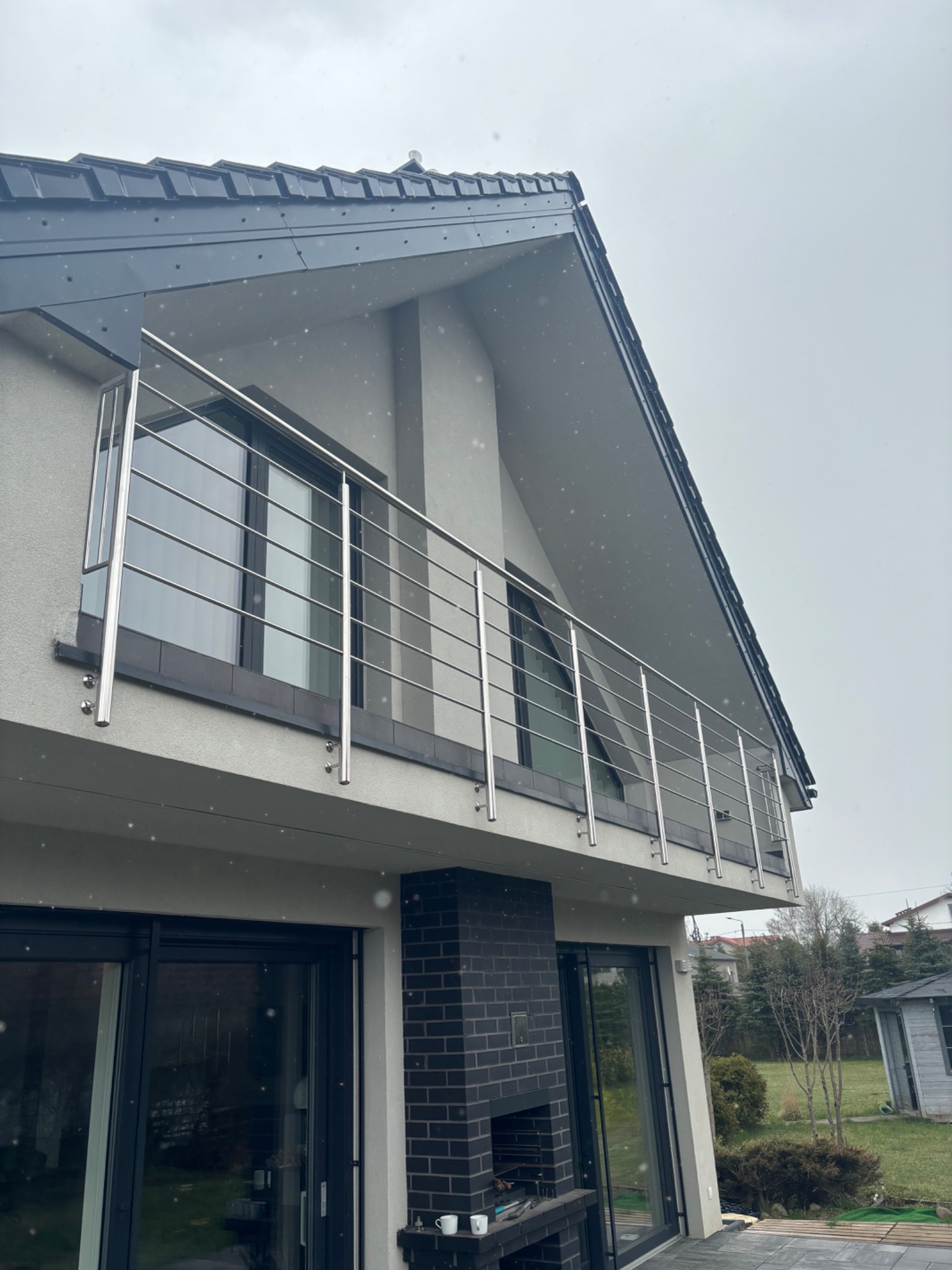 Nowoczesna balustrada ze stali nierdzewnej na balkonie domu w Goszczynie, widok z dołu, pochmurna pogoda.