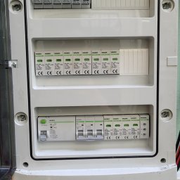 PIEDOX Piotr Pałka - Otwarta skrzynka rozdzielcza z zamontowanymi bezpiecznikami i ogranicznikami przepięć marki Noark, widoczne przewody elektryczne.