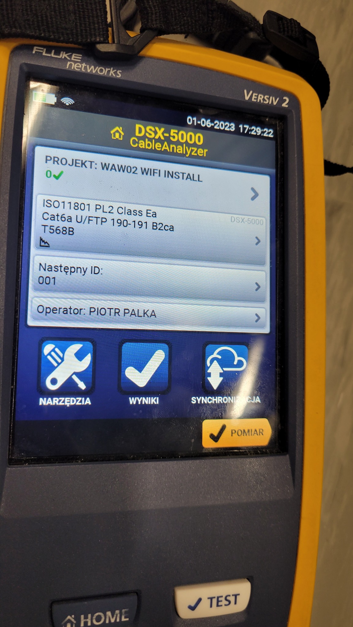 Ekran analizatora okablowania Fluke DSX-5000 CableAnalyzer, wyświetlający parametry testu sieciowego, w tym projekt 'WAW02 WIFI INSTALL', standard ISO11801 PL2 Class Ea, Cat6a U/FTP, oraz nazwę...