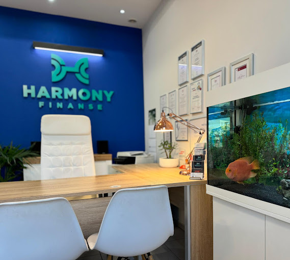 Biuro Harmony Finanse z akwarium, biurkiem, krzesłami i logo na niebieskiej ścianie, certyfikaty w ramkach na ścianie