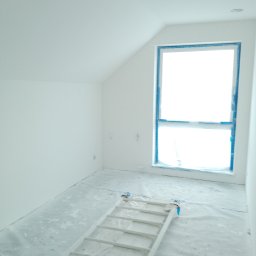 W.K Remonty i Wykończenia Wnętrz - Poddasze po świeżym pomalowaniu na biało, zabezpieczone okno taśmą malarską, rozłożona drabina na folii ochronnej, przygotowane do dalszych prac wykończeniowych.