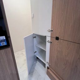 MD STUDIO MEBLE NA WYMIAR Maja Dziedzic - Otwarta szafka z półkami w zabudowie, fronty z drewna i bieli, widoczne okucia. Minimalistyczny design, jasne wnętrze, marmurowe płytki podłogowe.