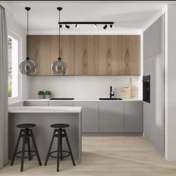 Usługi wykończeniowe i naprawcze - Nowoczesna kuchnia w odcieniach szarości i drewna z wyspą i dwoma czarnymi hokerami, oświetlona wiszącymi lampami kulami i reflektorami sufitowymi.