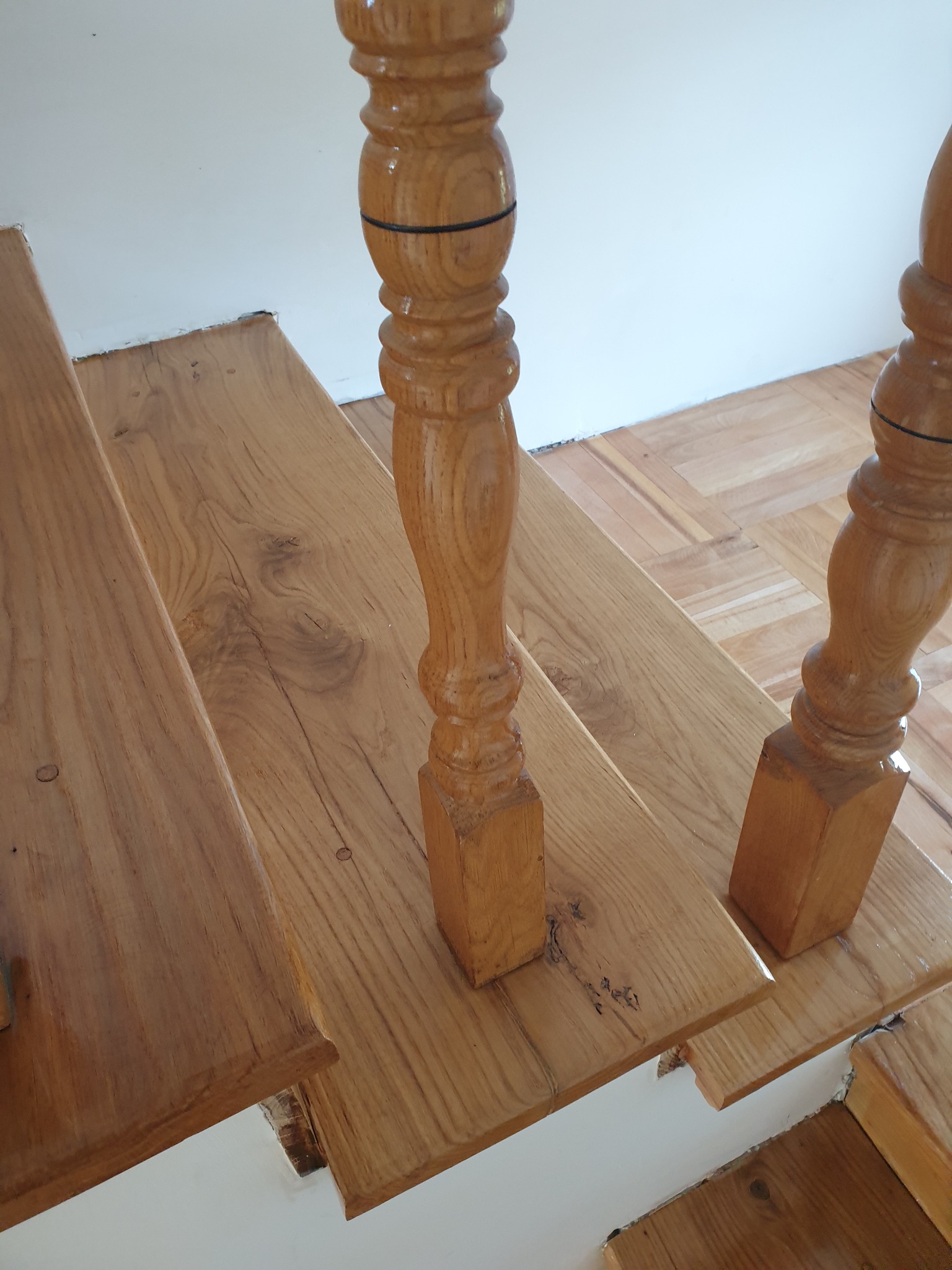 Drewniane schody z ozdobnymi balustradami, widok z góry. Naturalne usłojenie drewna i ciepła kolorystyka. Schody po renowacji.