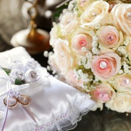 PSPHOTO Studio fotograficzne i filmowe NYSA - Bukiet ślubny z bladoróżowych róż z kryształkami i obrączki na białej satynowej poduszce z ozdobnymi różyczkami i fioletową wstążką.