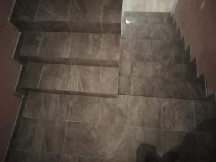 Schody wyłożone szarymi płytkami ceramicznymi z delikatnym wzorem marmuru, widok z góry, ciemne oświetlenie.