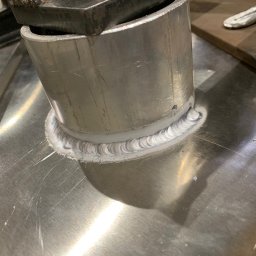 GLOBALSKILL SPÓŁKA Z OGRANICZONĄ ODPOWIEDZIALNOŚCIĄ - Szczegółowe zbliżenie spawu łączącego rurę z metalową płytą, widoczne ślady obróbki i zacisk narzędziowy na rurze. Precyzyjne, jasne spoiwo.