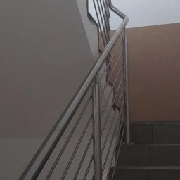 GLOBALSKILL SPÓŁKA Z OGRANICZONĄ ODPOWIEDZIALNOŚCIĄ - Wewnętrzne schody z metalową balustradą o minimalistycznym designie. Widoczne szare stopnie i jasna ściana. Ujęcie od dołu, podkreślające linię poręczy.