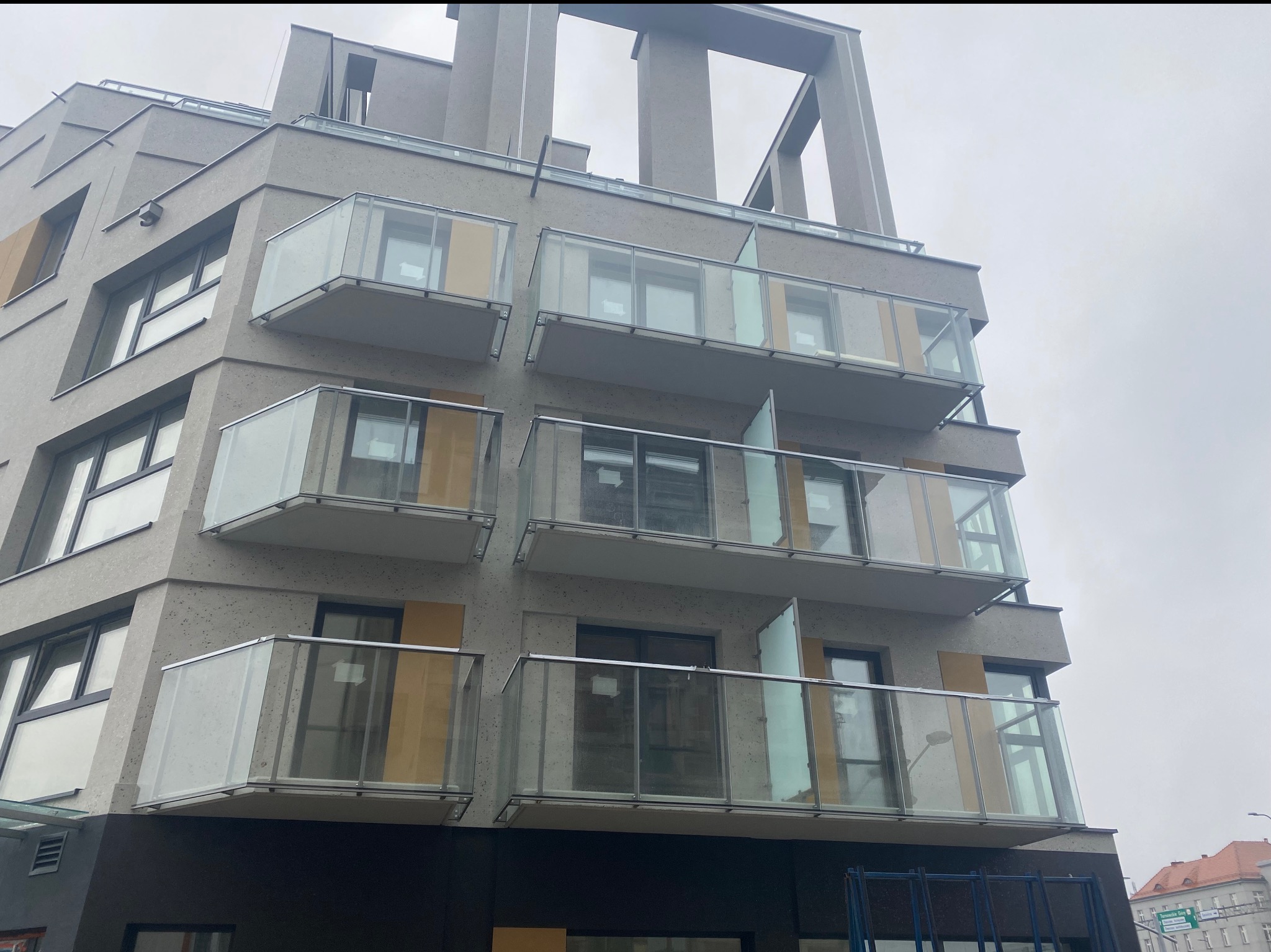 Nowoczesny budynek z balkonami z balustradami ze szkła i metalu. Ujęcie z dołu podkreśla architekturę budynku i minimalistyczny styl.