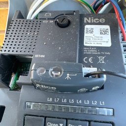 Automatyka Energetyka Zabezpieczenia - Sterownik bramy Nice POA3/A z widocznymi przyciskami Close, Stop/Set i Open oraz diodami L1-L8. Widoczne przewody i elementy elektroniki.