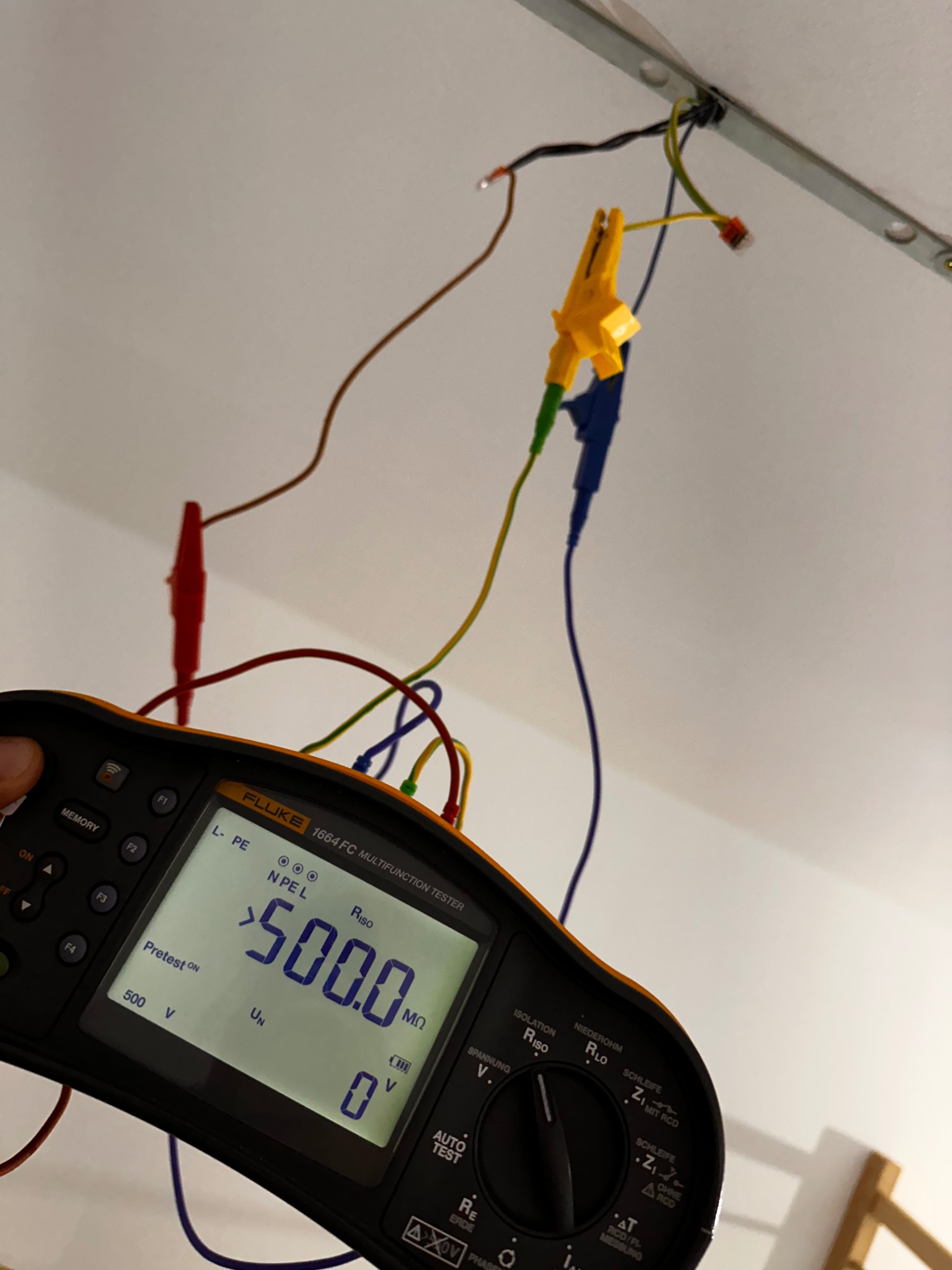 Miernik Fluke 1664 FC podczas pomiaru rezystancji izolacji instalacji elektrycznej. Widoczne przewody pomiarowe z krokodylkami podłączone do instalacji.