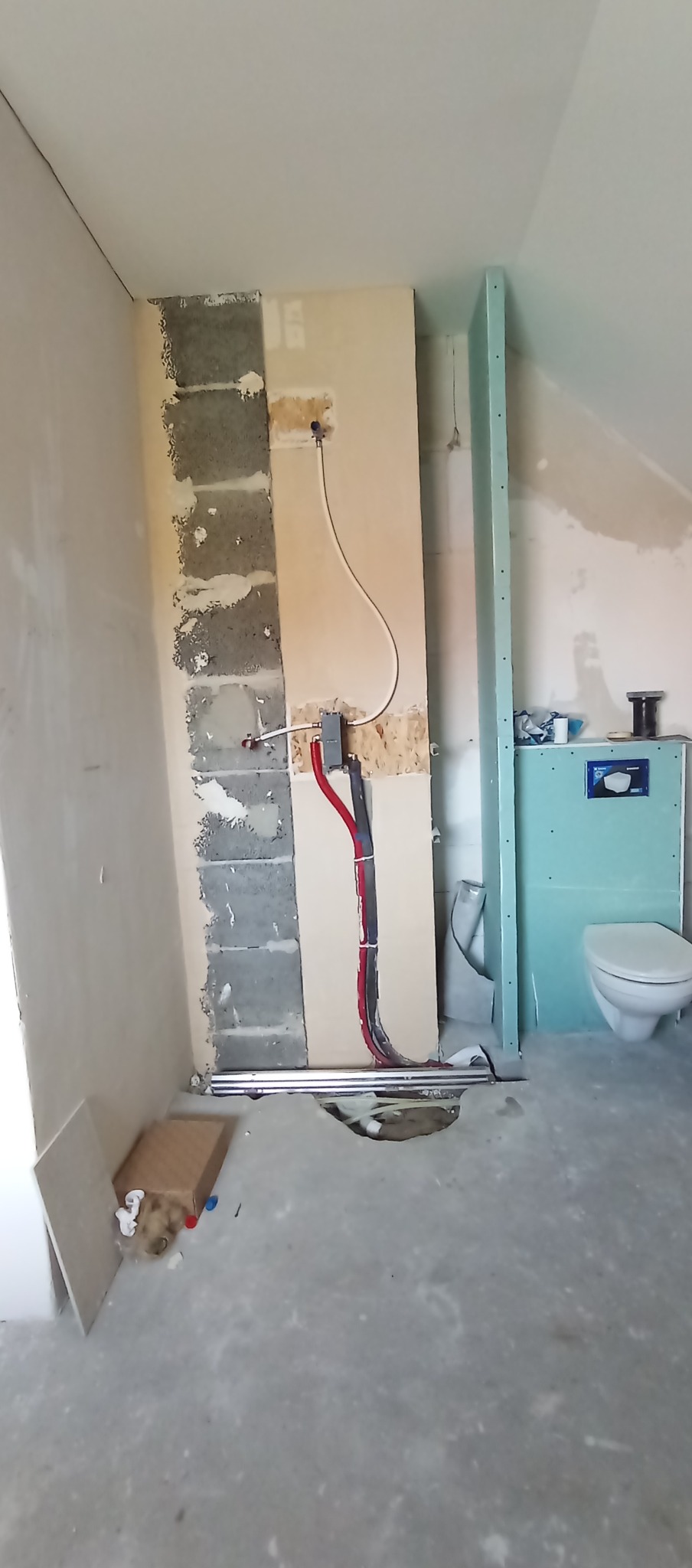 Remont łazienki w trakcie: widoczne rury instalacji wodnej i kanalizacyjnej, częściowo obudowane ściany, stelaż podtynkowy WC. Prace instalacyjne w surowym wnętrzu.