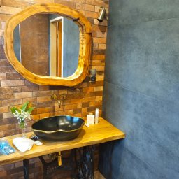 REMONTY A-Z Andrzej Kiewra - Rustykalna łazienka z umywalką w stylu retro na podstawie maszyny do szycia, lustrem w drewnianej ramie i ścianą z cegły oraz szarych płytek.